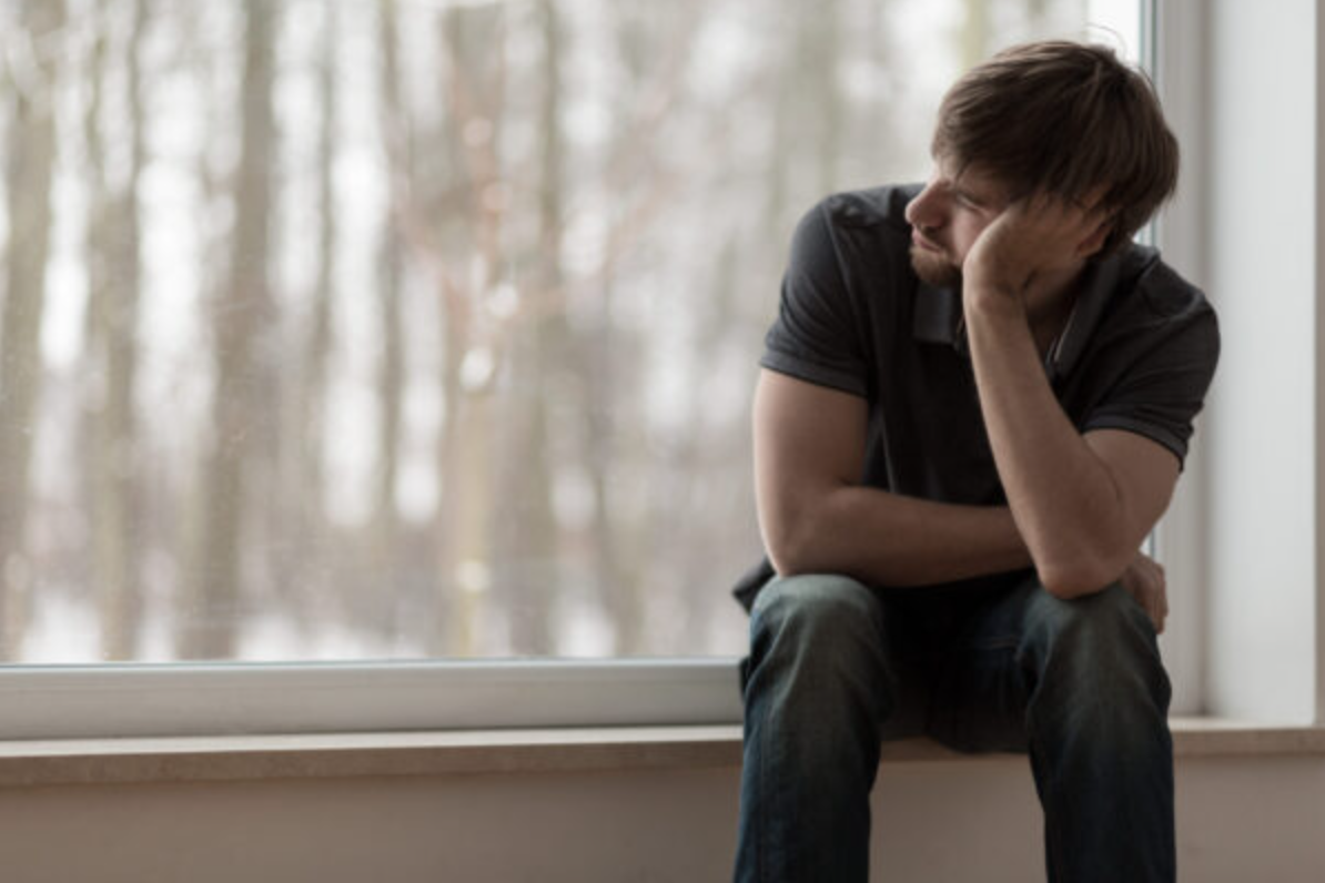 Young miserable depressed man sitting and thinking